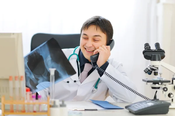 Médico sorridente segurando pacientes roentgen e falando ph — Fotografia de Stock