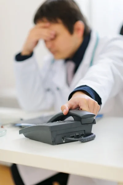Frustrated medical doctor picking up phone handset — Stock Photo, Image