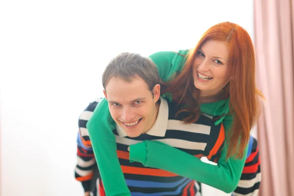 Smiling redhead girl piggybacking boyfriend — Stock Photo, Image