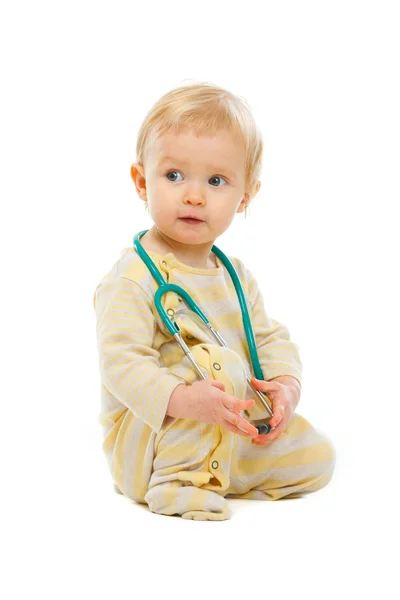 Dziecko z stetoskop wyglądający na stronie na białym tle — Zdjęcie stockowe