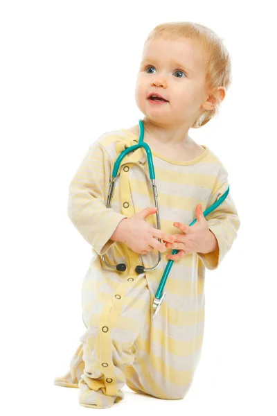 Baby with stethoscope looking in corner on white background — Stock Photo, Image