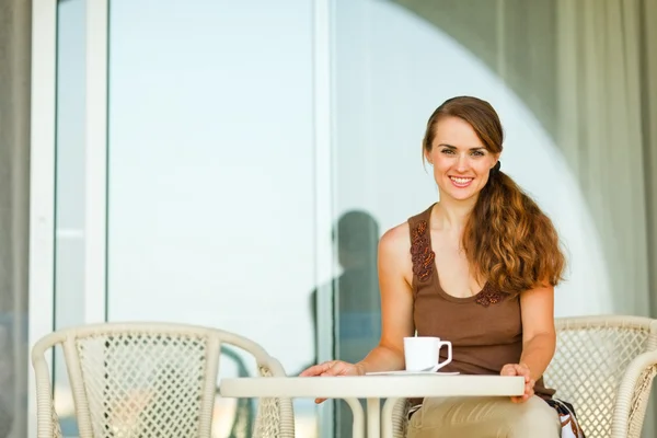Ευτυχής νεαρή γυναίκα που κάθεται στην βεράντα με φλιτζάνι τσάι — Φωτογραφία Αρχείου