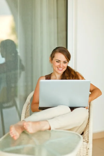 与笔记本电脑的露台上放松的微笑年轻女人 — 图库照片