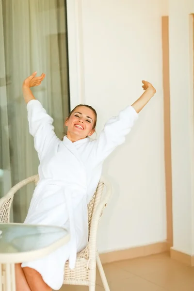 Woman in bathrobe stretching on terrace — Stock Photo, Image