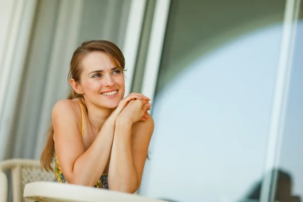 Женщина, сидящая на террасе и смотрящая на копирайт — стоковое фото