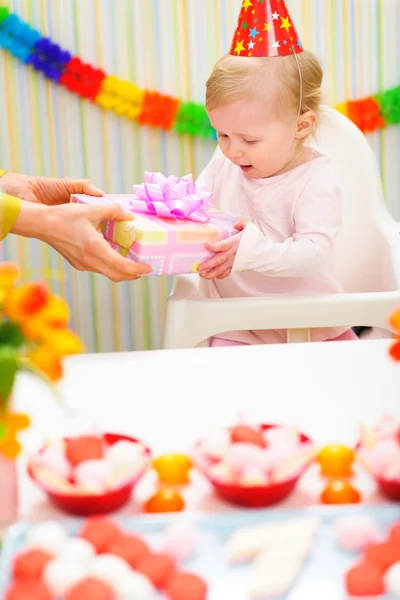 Удивлённый ребёнок получает подарок на первый день рождения — стоковое фото