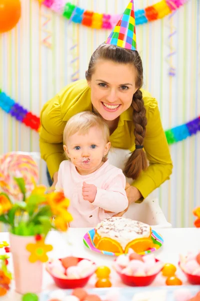 Smiling mother and eat smeared baby on birthday celebration part — Stock Photo, Image