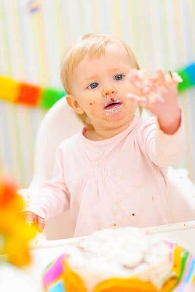 Portrait of baby smeared in birthday cake