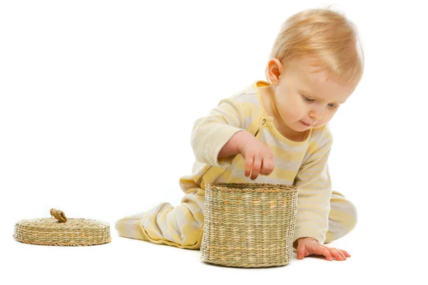 Interested baby putting hand in basket on white background Royalty Free Stock Photos