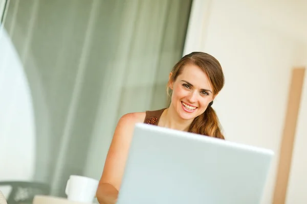 Portret van lachende vrouw die op laptop werkt Stockfoto