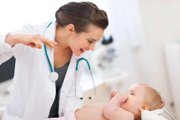 Pediatric doctor playing with baby on survey Stock Picture