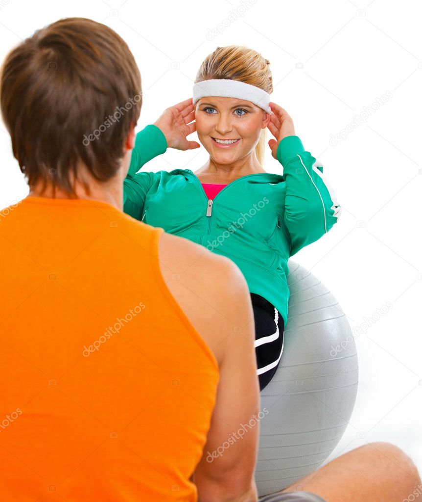 Personal sport trainer helping healthy girl making abdominal cru