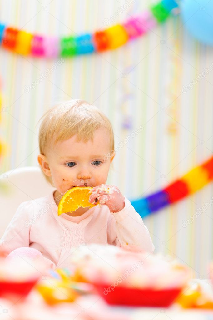 Baby eating orange on first birthday celebration party