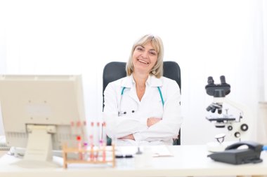 Happy mature doctor woman at office clipart