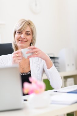 Smiling senior business woman having coffee break clipart