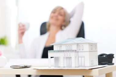 Closeup on scale model of house and happy architect woman in bac clipart