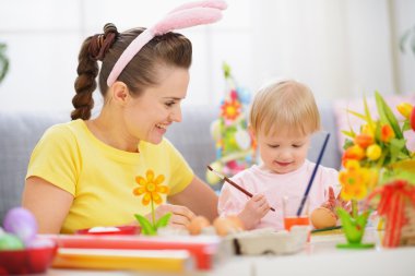 Mother and baby painting on Easter eggs clipart