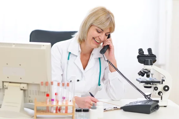 Uśmiechający się starszy lekarz mówiąc telefon w urzędzie — Zdjęcie stockowe