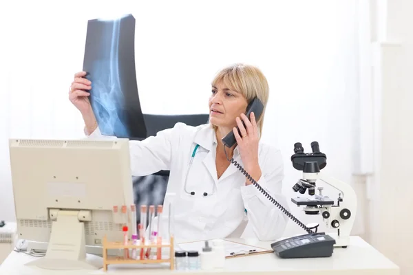 Vedoucí lékař žena mluvící telefon a při pohledu na roent pacientů — Stock fotografie