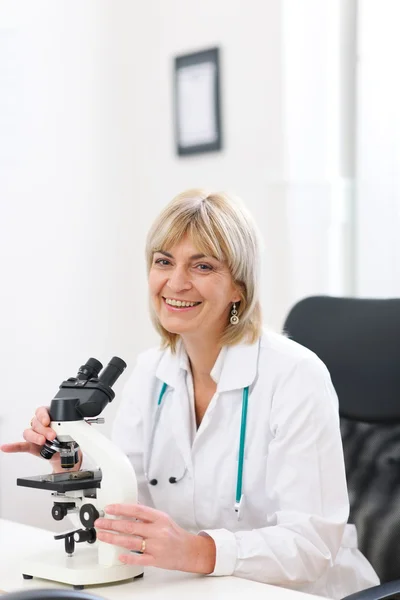 Mulher médico senior sorridente trabalhar com microscópio em laborator — Fotografia de Stock