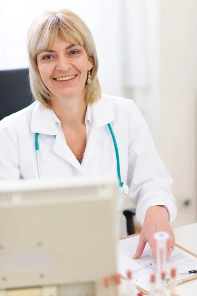Portrait of smiling senior doctor woman working on computer — Stock Photo, Image