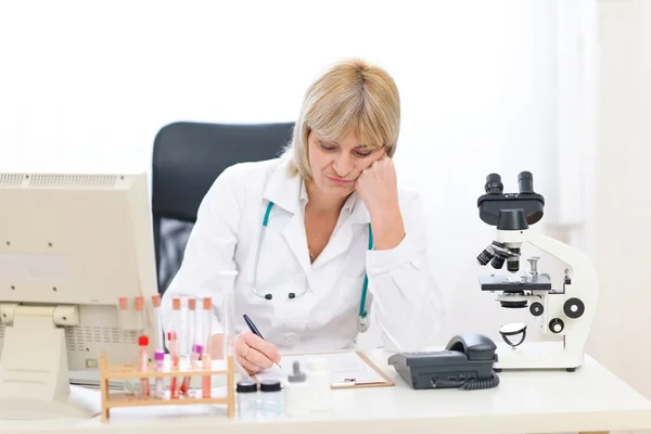 Kobieta znudzona starszy lekarz pracuje w urzędzie — Zdjęcie stockowe