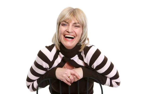 Портрет улыбающейся женщины средних лет, сидящей на стуле — стоковое фото