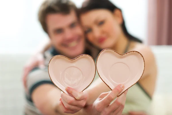 Closeup on porcelain hearts in hands of young couple — Stock Photo, Image