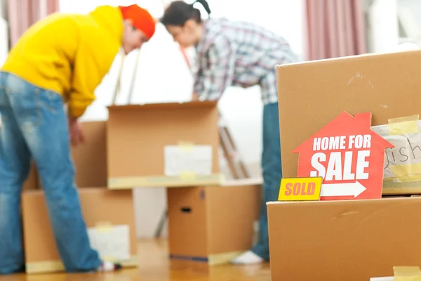 Home for sale sign with sold sticker and unpacking young family — Stock Photo, Image