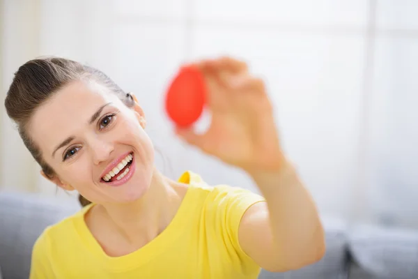 Усміхнена жінка показує червоне пасхальне яйце — стокове фото
