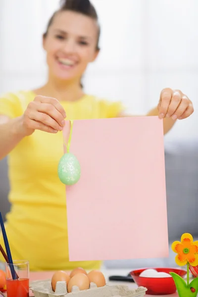 Mulher sorridente segurando papel em branco com ovo de Páscoa — Fotografia de Stock