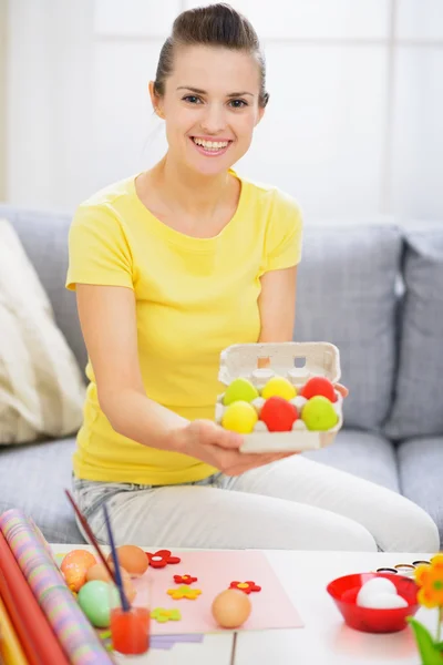 Mulher sorridente mostrando bandeja com ovos de Páscoa coloridos — Fotografia de Stock