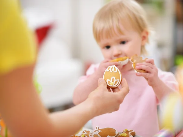 Mãe dando biscoito de bebê em forma de ovo de Páscoa. Foco em cooki — Fotografia de Stock