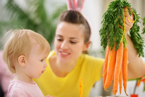 Мама показывает ребенку кучу моркови — стоковое фото