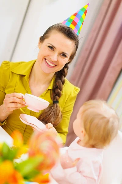 Mother drinking tea on babies birthday party — Stock Photo, Image