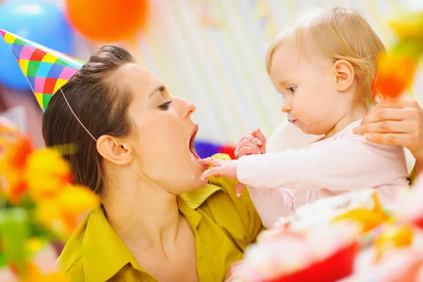 Baby feeding mother with birthday cake — Stock Photo, Image