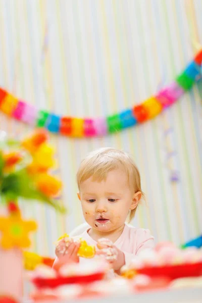 Eat smeared baby eating orange at birthday party — Stock Photo, Image