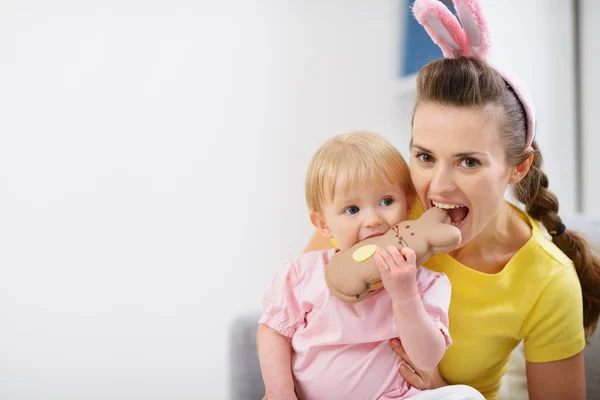 Mor och barn biter choklad påsk kanin cookie Royaltyfria Stockbilder