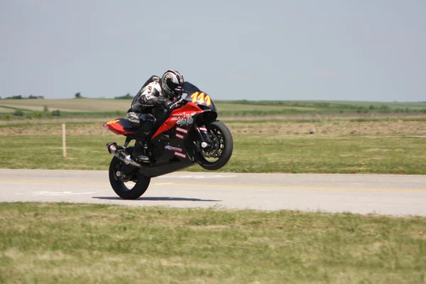 Lonely motorbike speeding up on rear wheel — Stock Photo, Image
