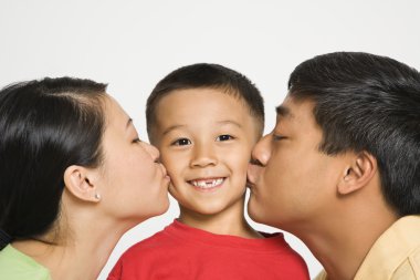 Parents kissing boy. clipart