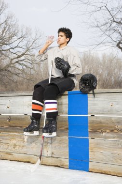 Hockey boy drinking water. clipart