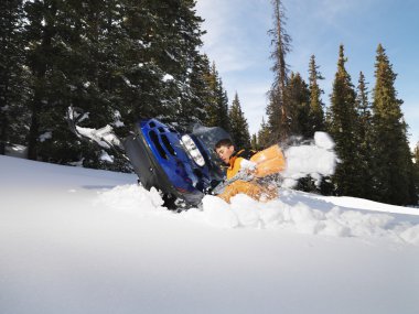 Man with stuck snowmobile. clipart