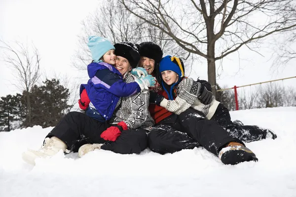 Familie zitten in de sneeuw. — Stockfoto
