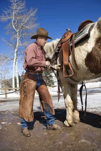 Cowboy mettere sella su cavallo — Foto Stock