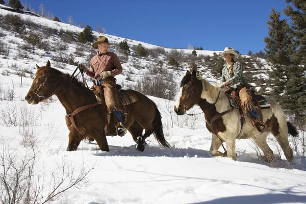 Hombre y mujer montando caballos en la nieve —  Fotos de Stock