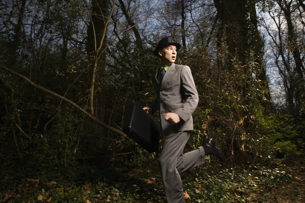 Jovem empresário correndo em bosques — Fotografia de Stock