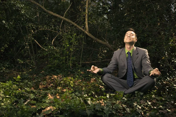 Бизнесмен, сидящий в медитации снаружи — стоковое фото