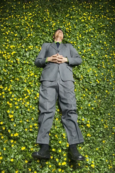 Молодой бизнесмен, лежащий в цветочном пятачке — стоковое фото