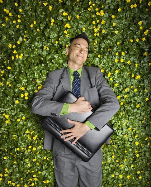 Geschäftsmann liegt im Blumenbeet — Stockfoto