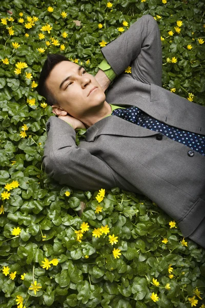 Бизнесмен, лежащий в цветочном пятачке — стоковое фото